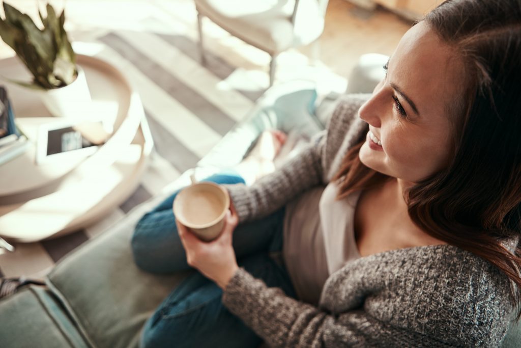 Shot of a young woman relaxing at home with a cup of coffee